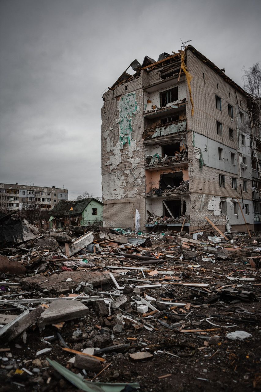 A damaged apartment block stands among the ruins of urban combat.